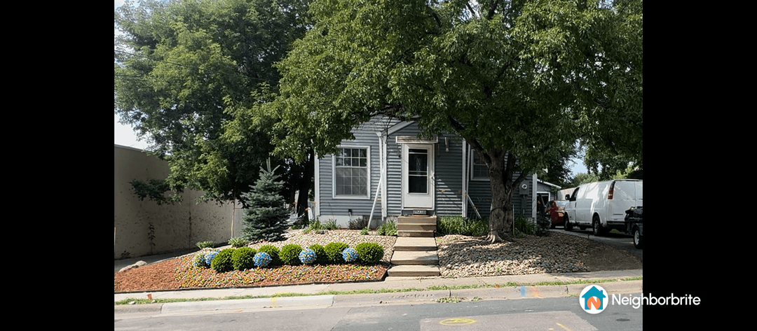 A house with a rock garden featuring minimal plants and a few shrubs.