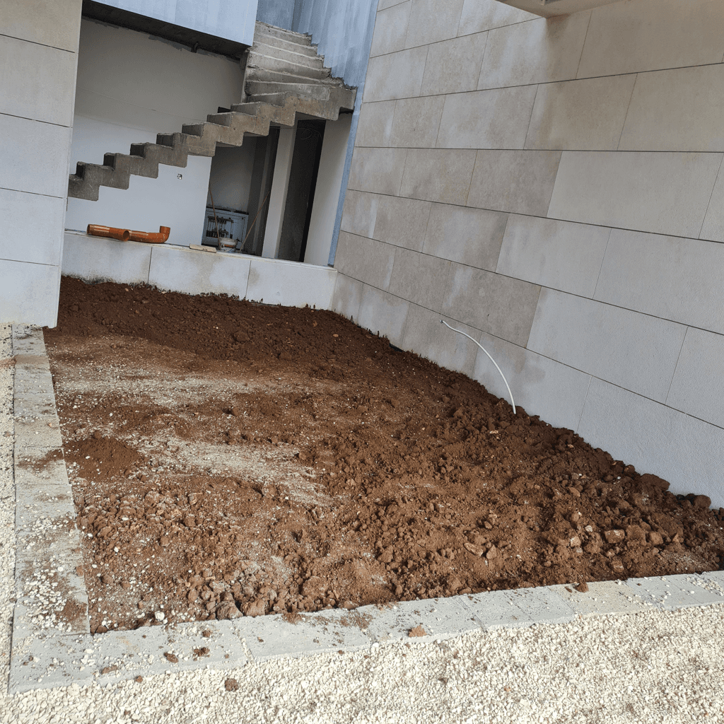 Excavated courtyard area with soil and stone borders.