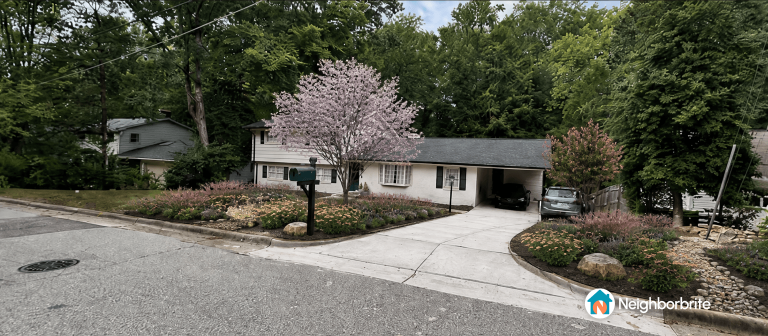 A front yard with a pink flowering tree and landscaped garden.