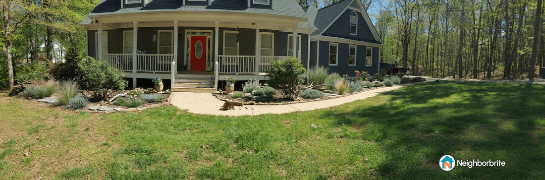 A front yard with landscaping, featuring plants and a porch.