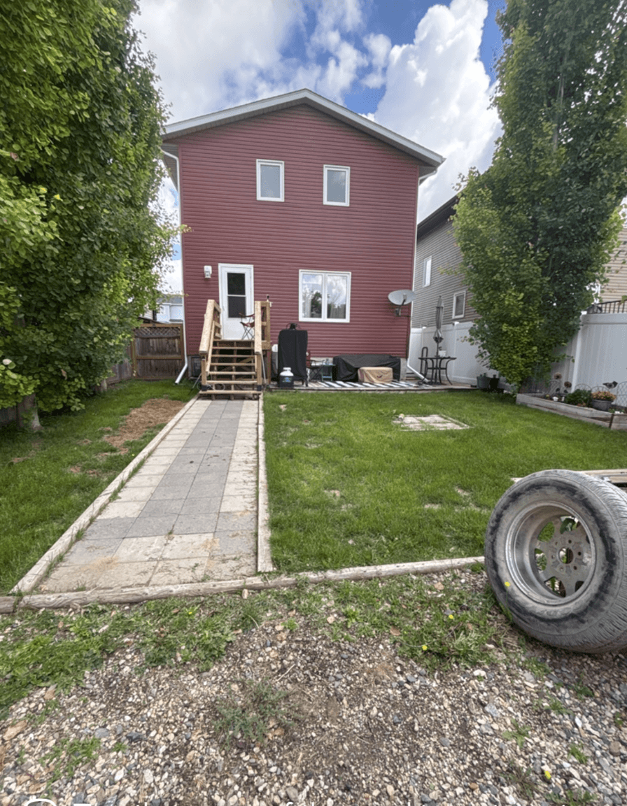 Backyard with grass, patio, and steps leading to a house.