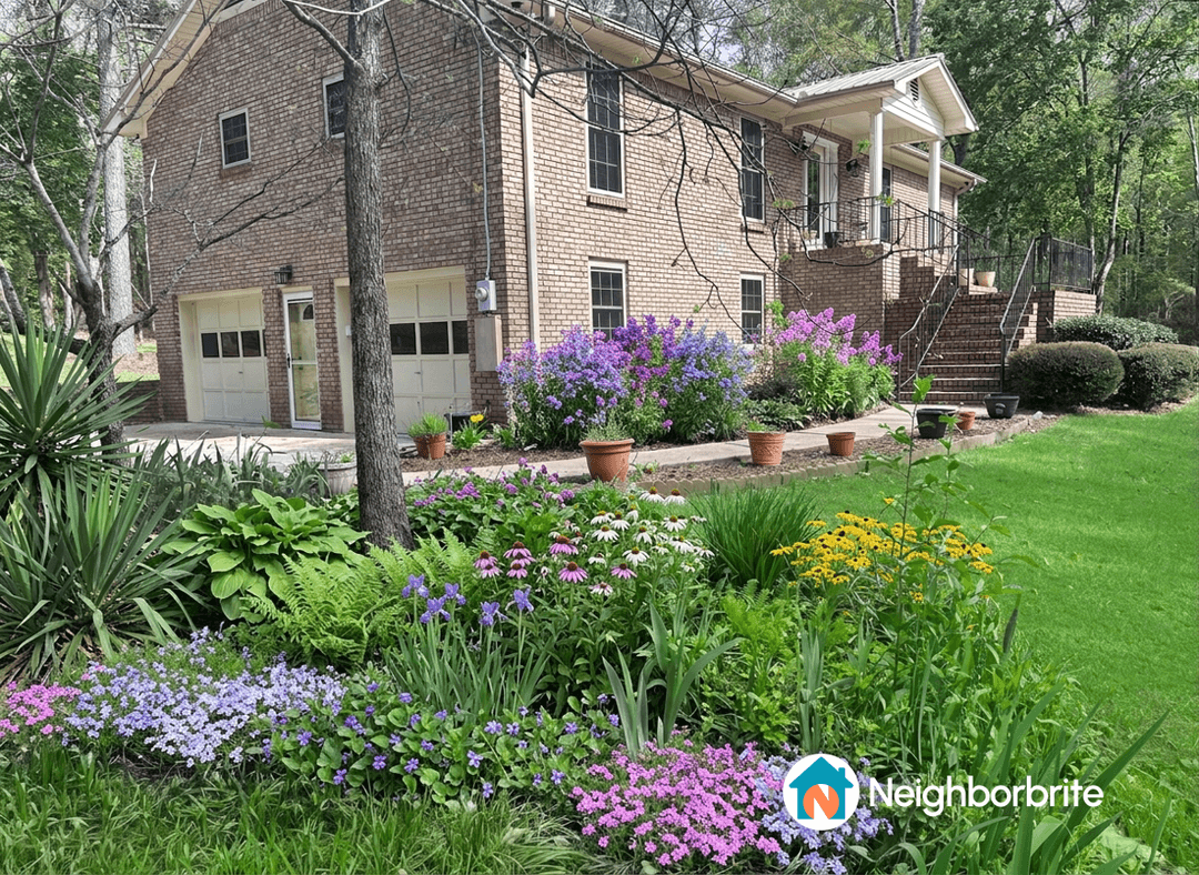 A well-maintained yard with colorful flower beds and a brick house.