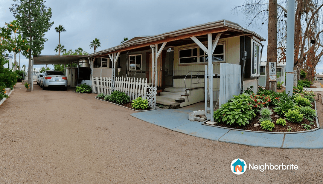 A garden area with various plants and a home in the background.