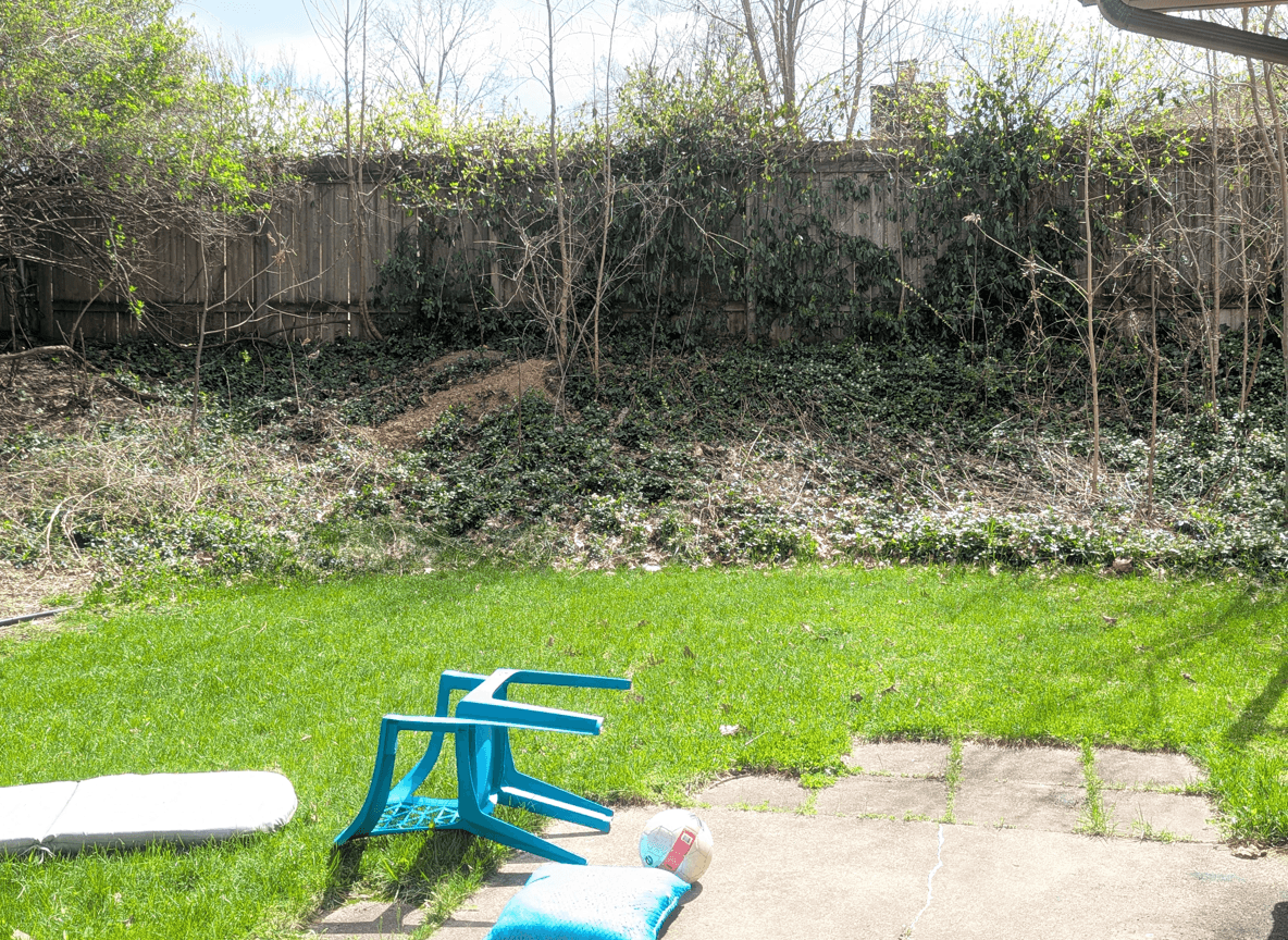 A sloped backyard area with grass, retaining wall ideas, and furniture.