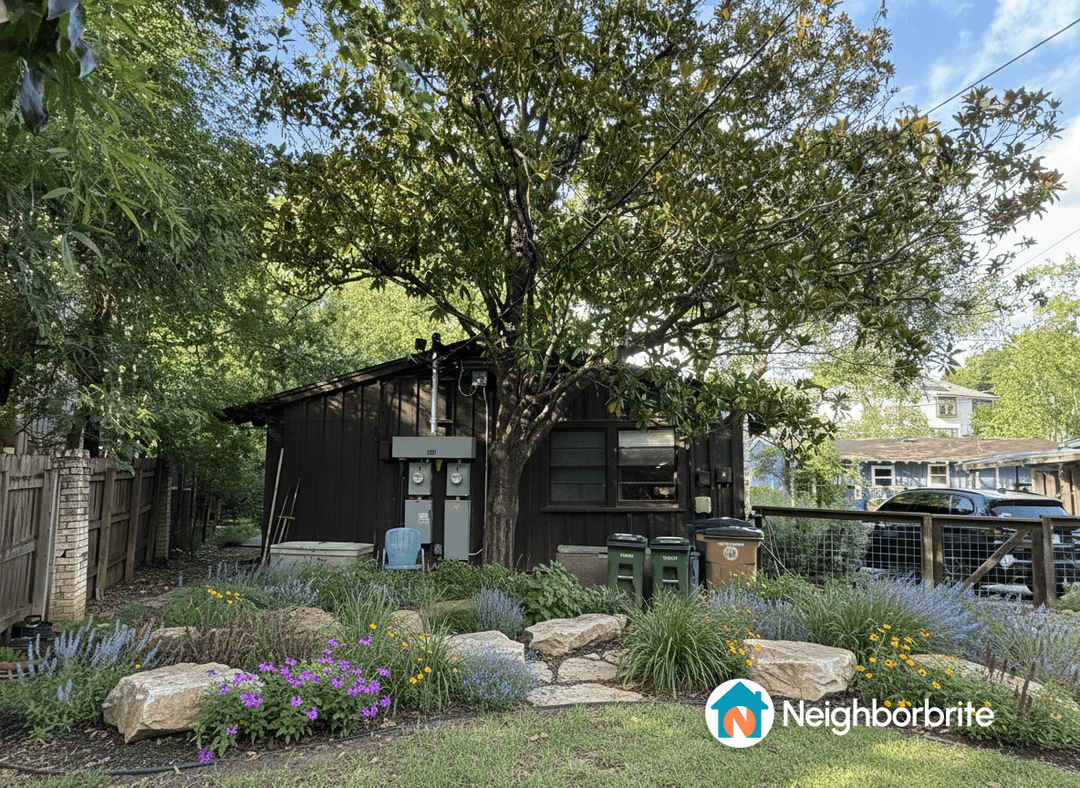 A landscaped yard with flowers, rocks, and a tree near a house.