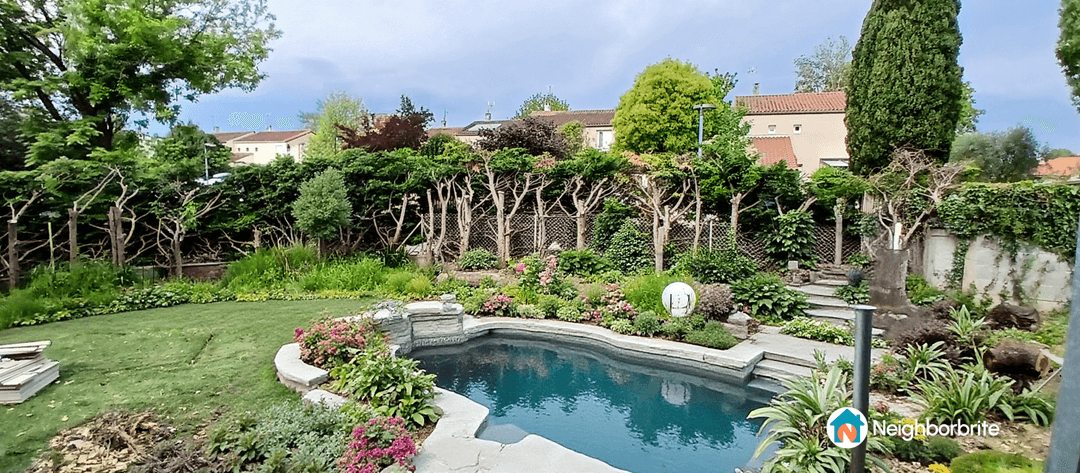 A garden with a pool, featuring newly added plants and greenery.