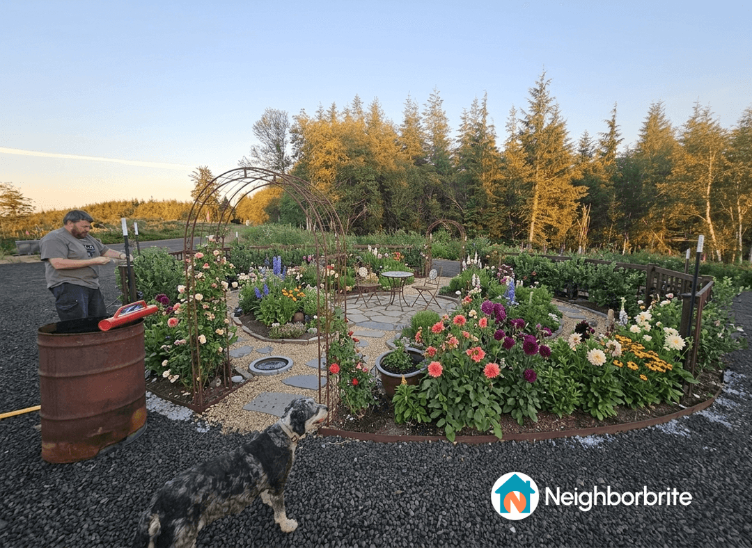 A garden with flowers, a man working, and a dog nearby.