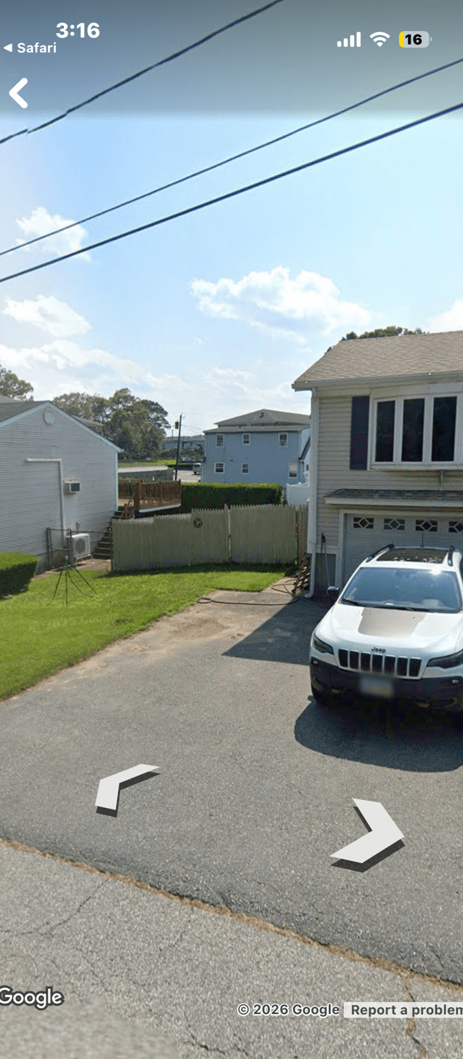 View of a side yard with a fence and parked car.