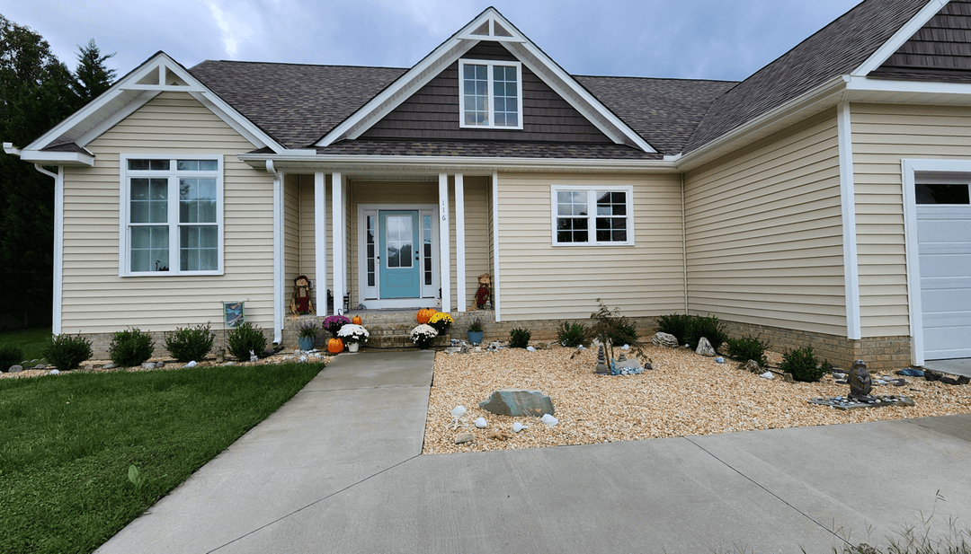 Front yard with decorative stones, plants, and colorful flowers.