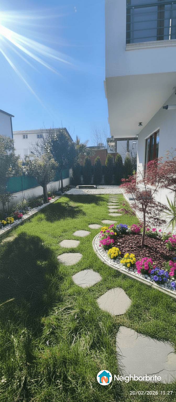 A well-designed backyard with flowers, grass, and stepping stones.