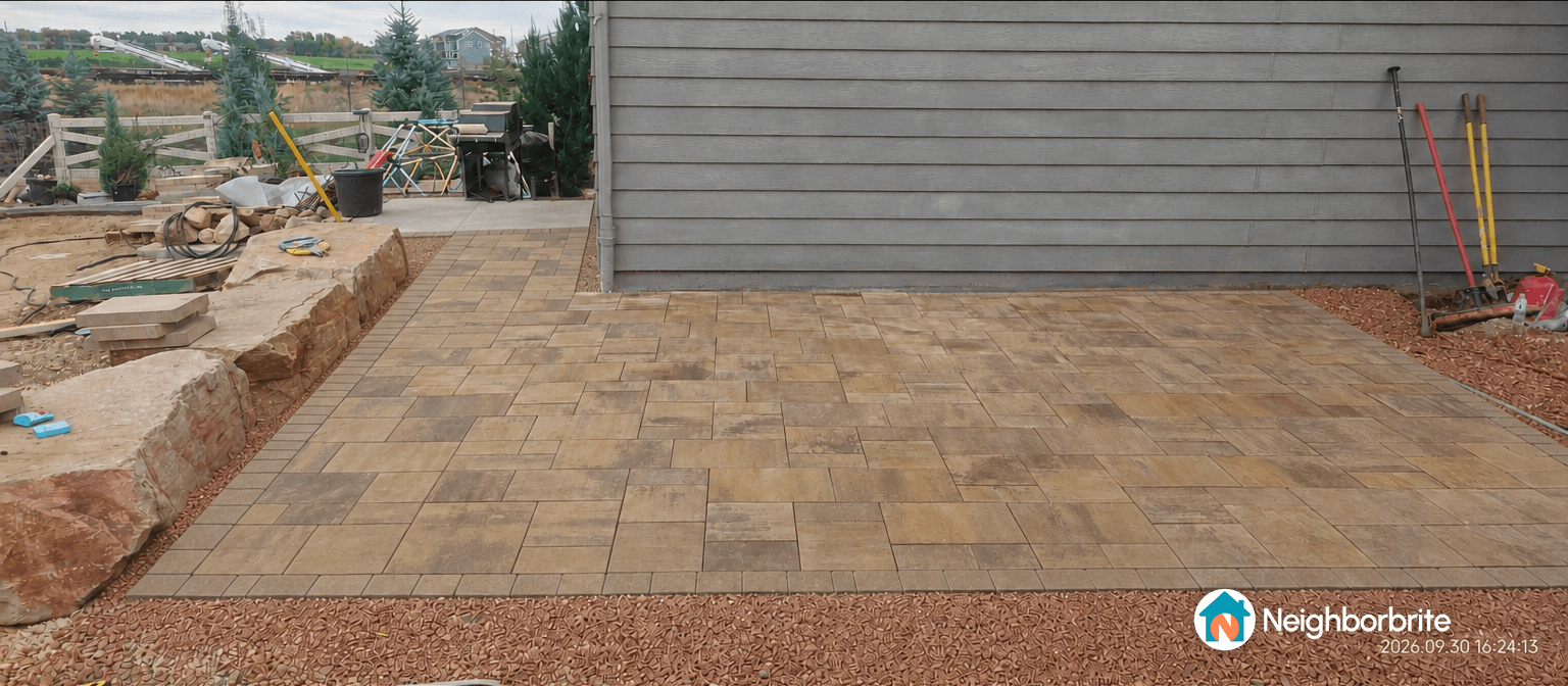 A patio with curved corners, showcasing stone tiles and landscaping.