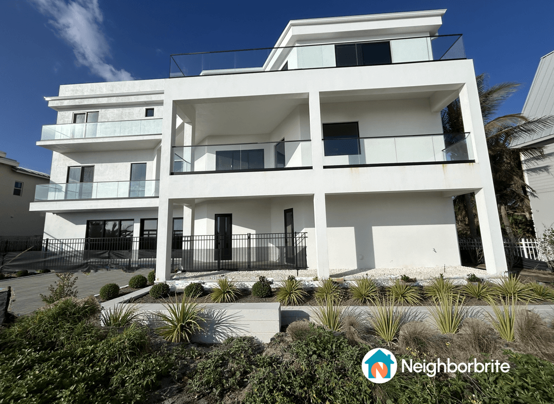 A modern multi-level home with glass balconies and landscaped yard.