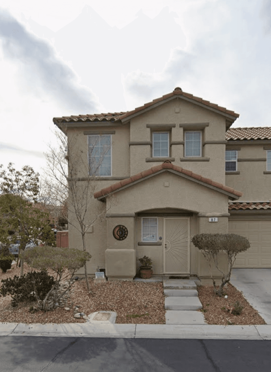 Front yard of a house in a desert climate with rocks and shrubs.