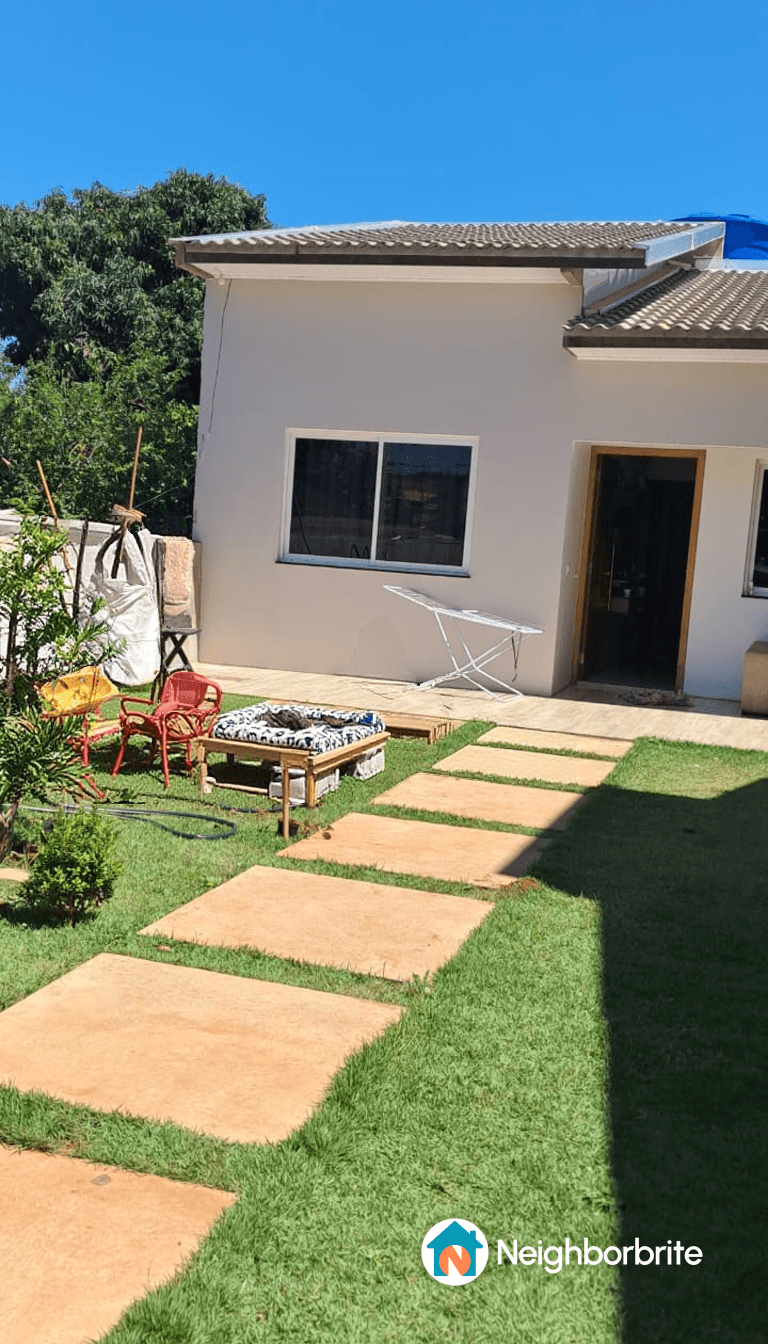 A sunny yard featuring a pathway, seating, and greenery.