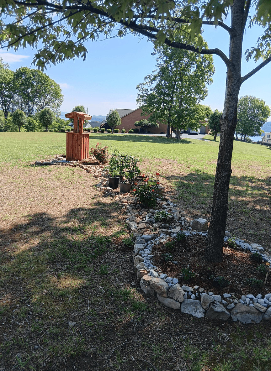 A minimalist Japanese garden design featuring a wooden structure and flower beds surrounded by stones.