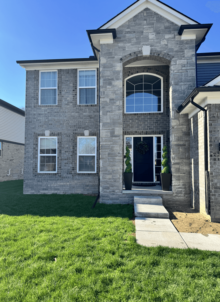 Front view of a house with a stone facade and lawn.