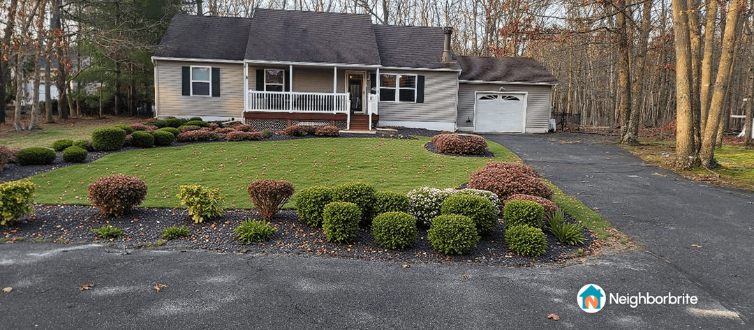A well-maintained yard with shrubs and flowers in front of a house.