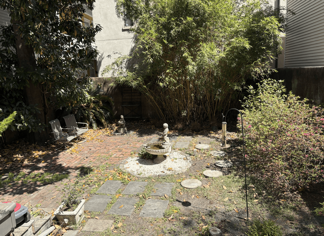 A Savannah courtyard with brick and stone paths, plants, and a fountain.