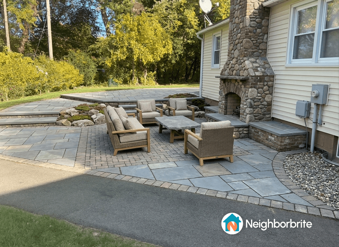 A beautifully designed backyard with stone patio and seating area.