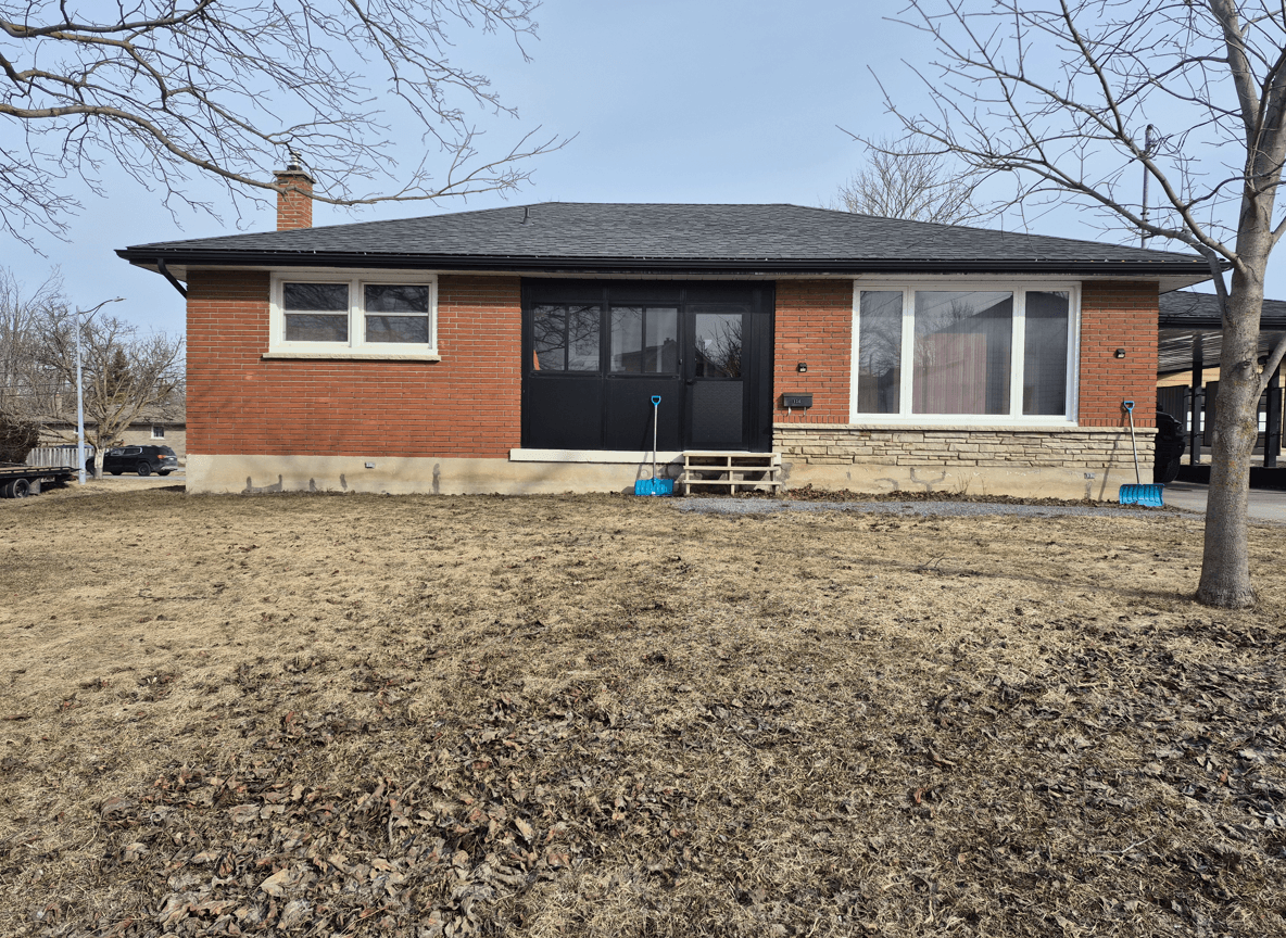 Front yard with brick house, bare lawn, and steps leading to porch.