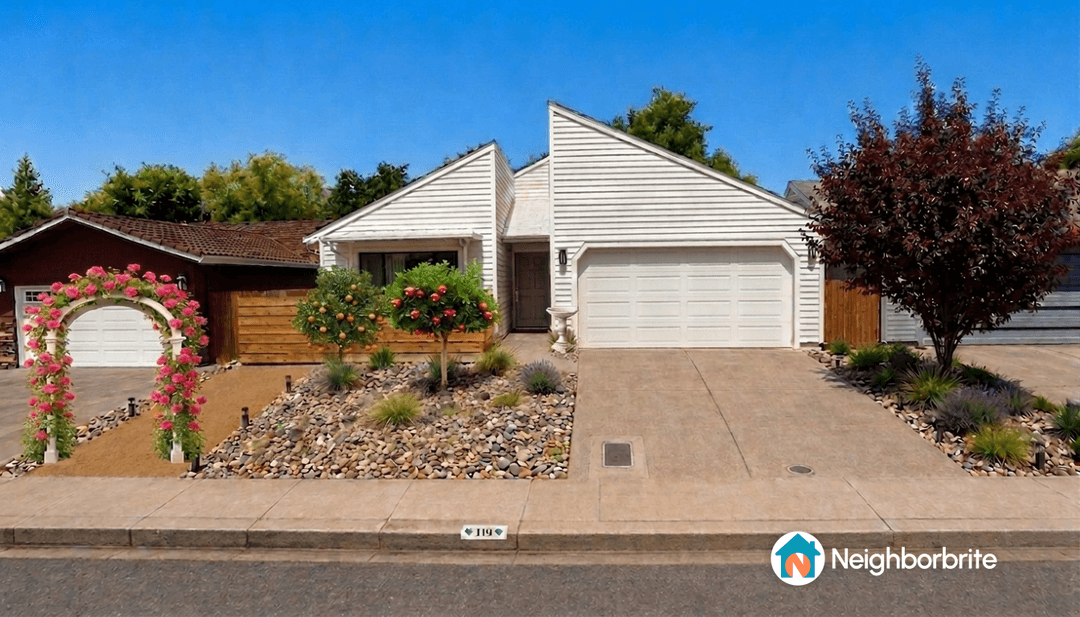 A charming home with a floral arch, orange trees, and landscaped stones.