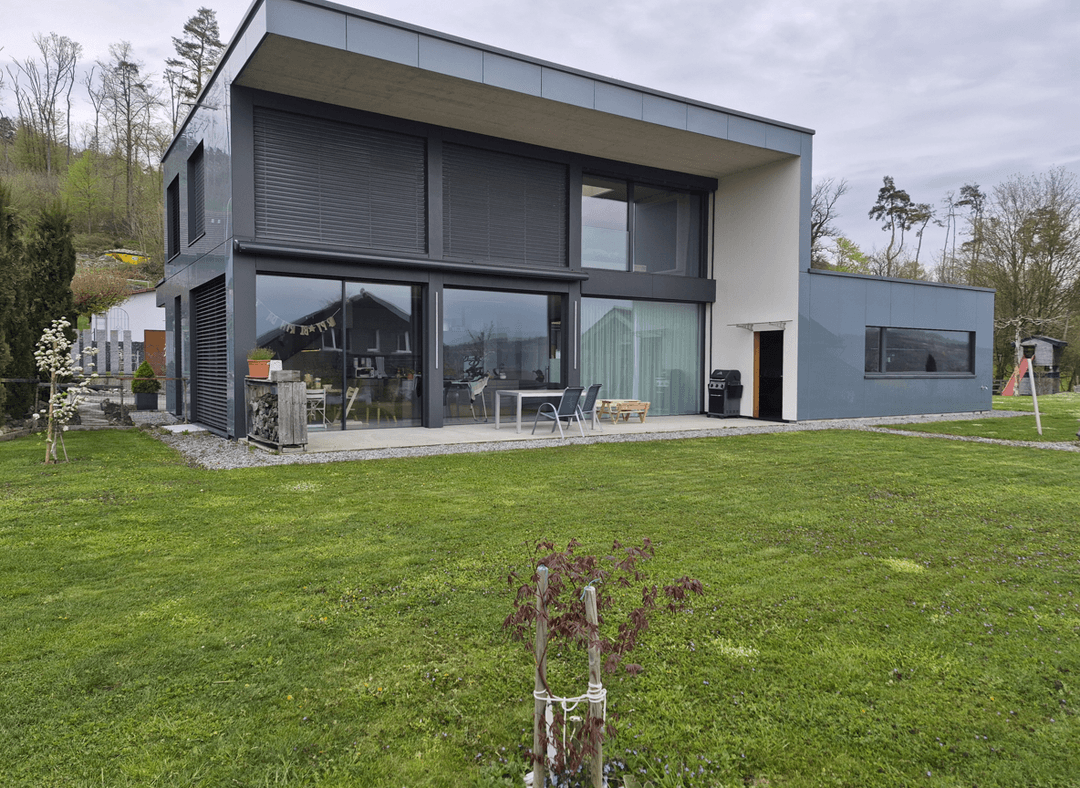 Modern home with large windows and green lawn.