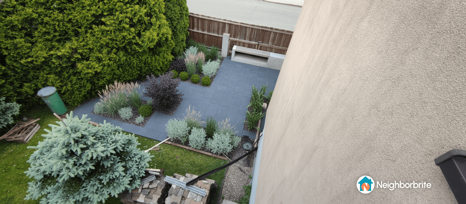 Overview of a yard with plants and paving, showing space for a garage entrance.