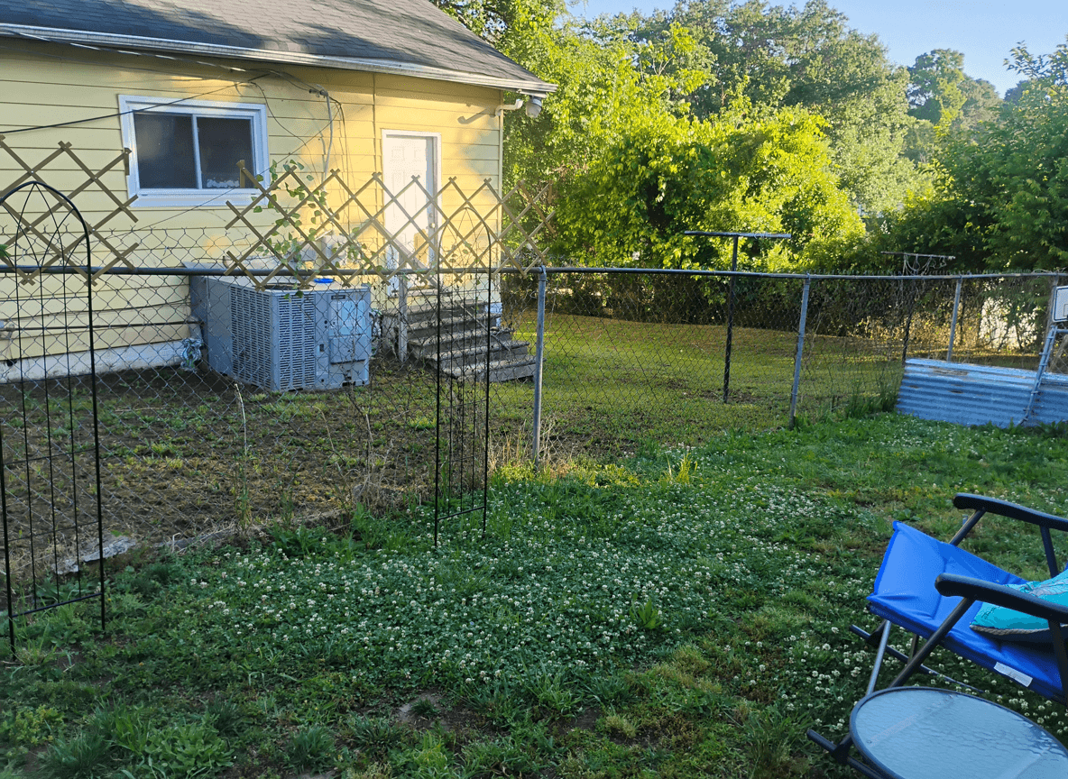 View of a backyard with a fence and space for planting trees.