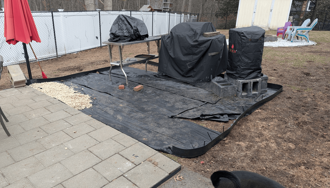 A yard area with black tarp, gravel, and covered items, seeking completion ideas.