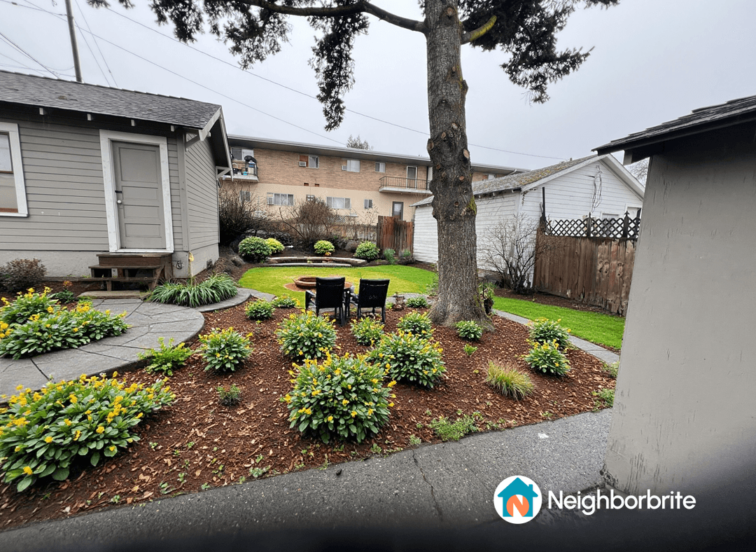 A landscaped yard featuring green plants and seating area.