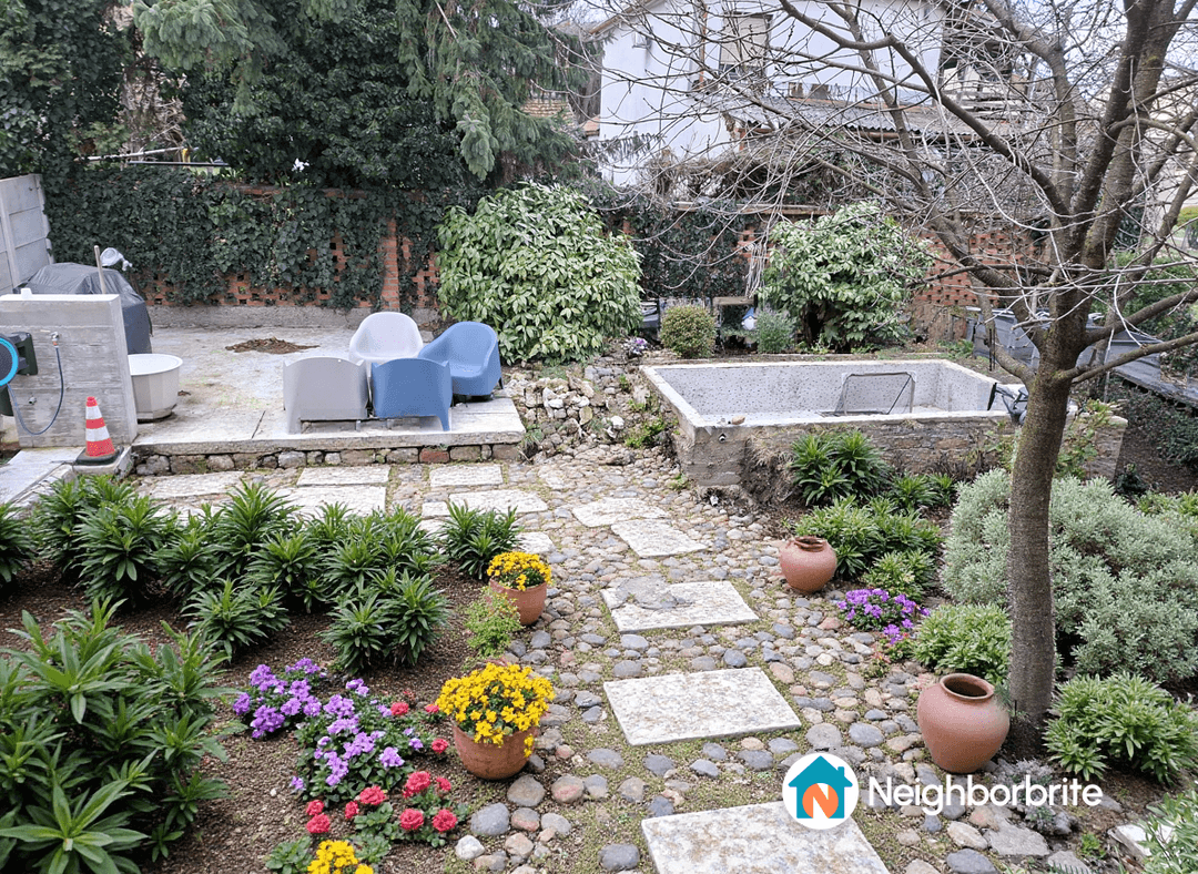 A landscaped yard with stone paths, plants, and seating area.