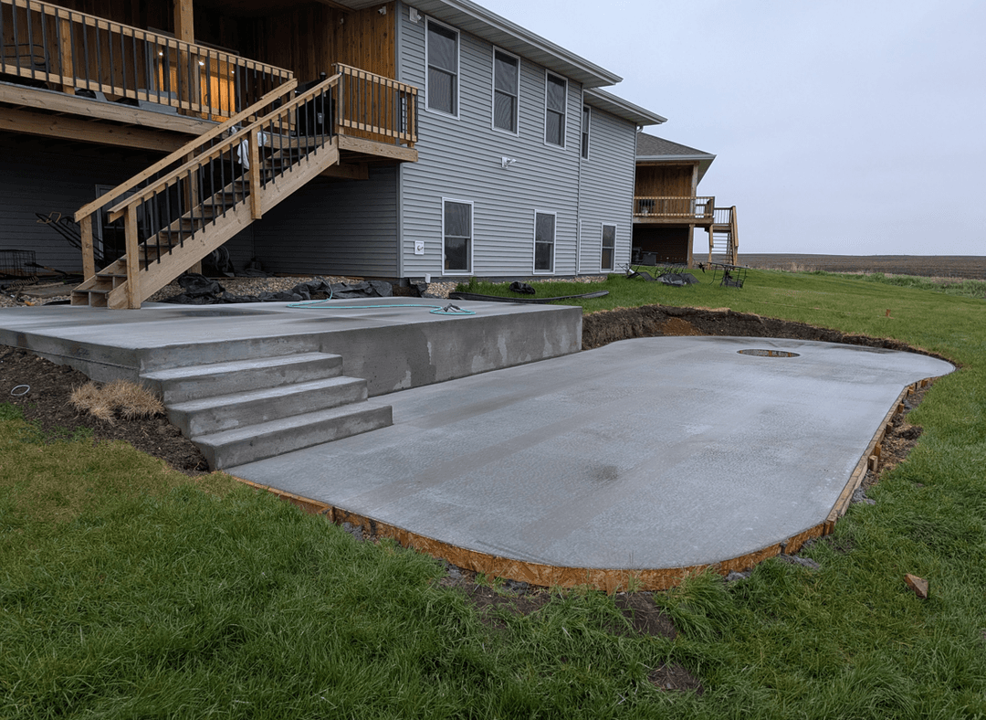 Concrete patio area with steps and grassy surroundings.