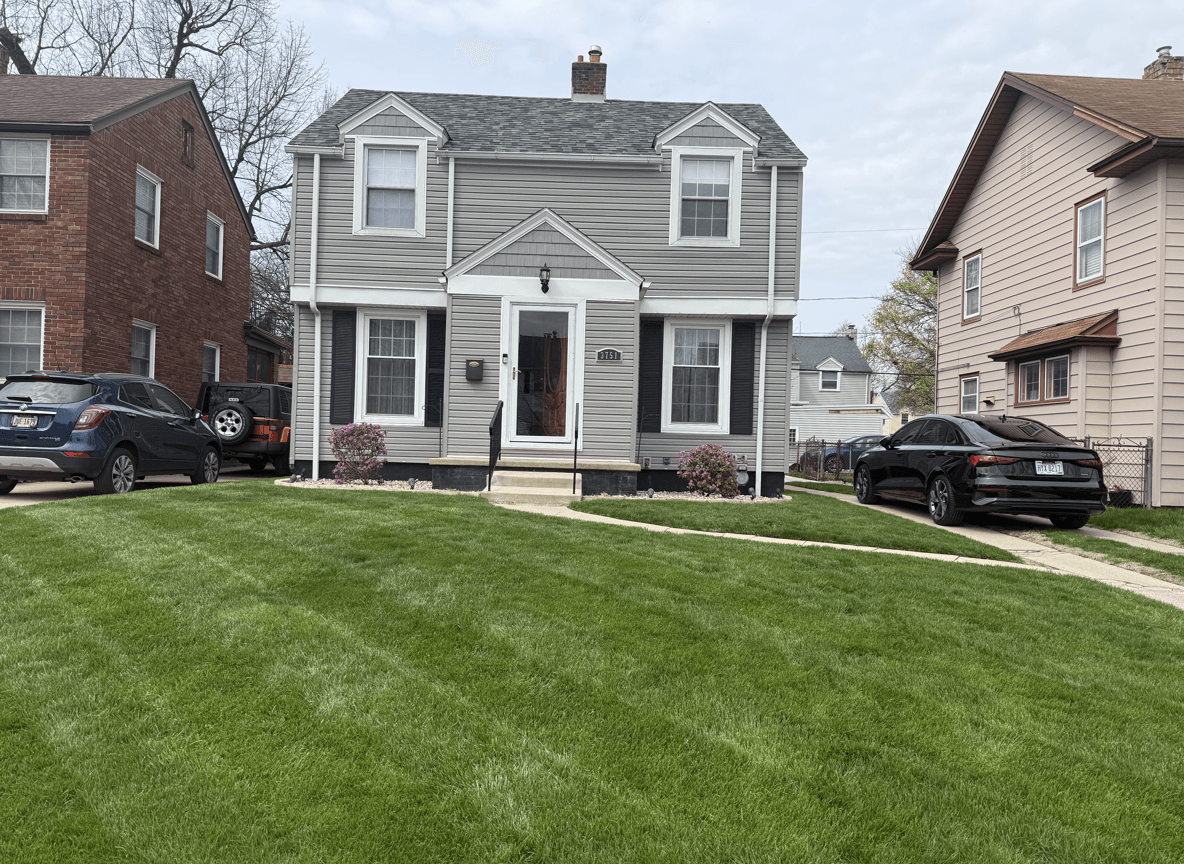 A well-maintained front yard with a gray house and blooming flowers.