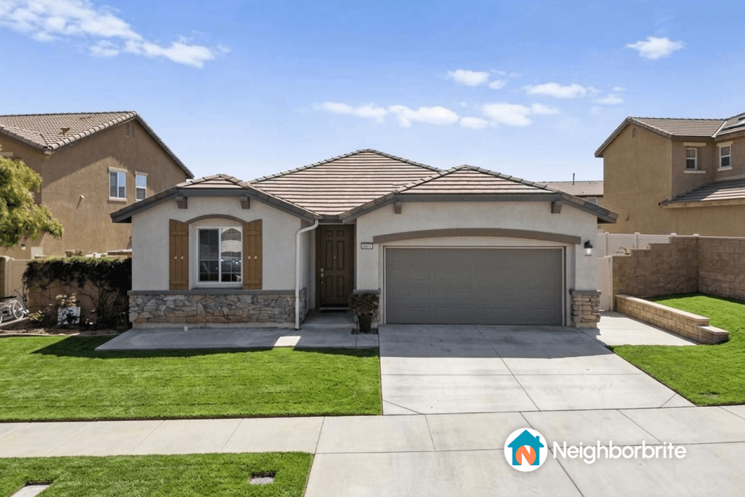 A well-maintained home with a green lawn and stone accents.