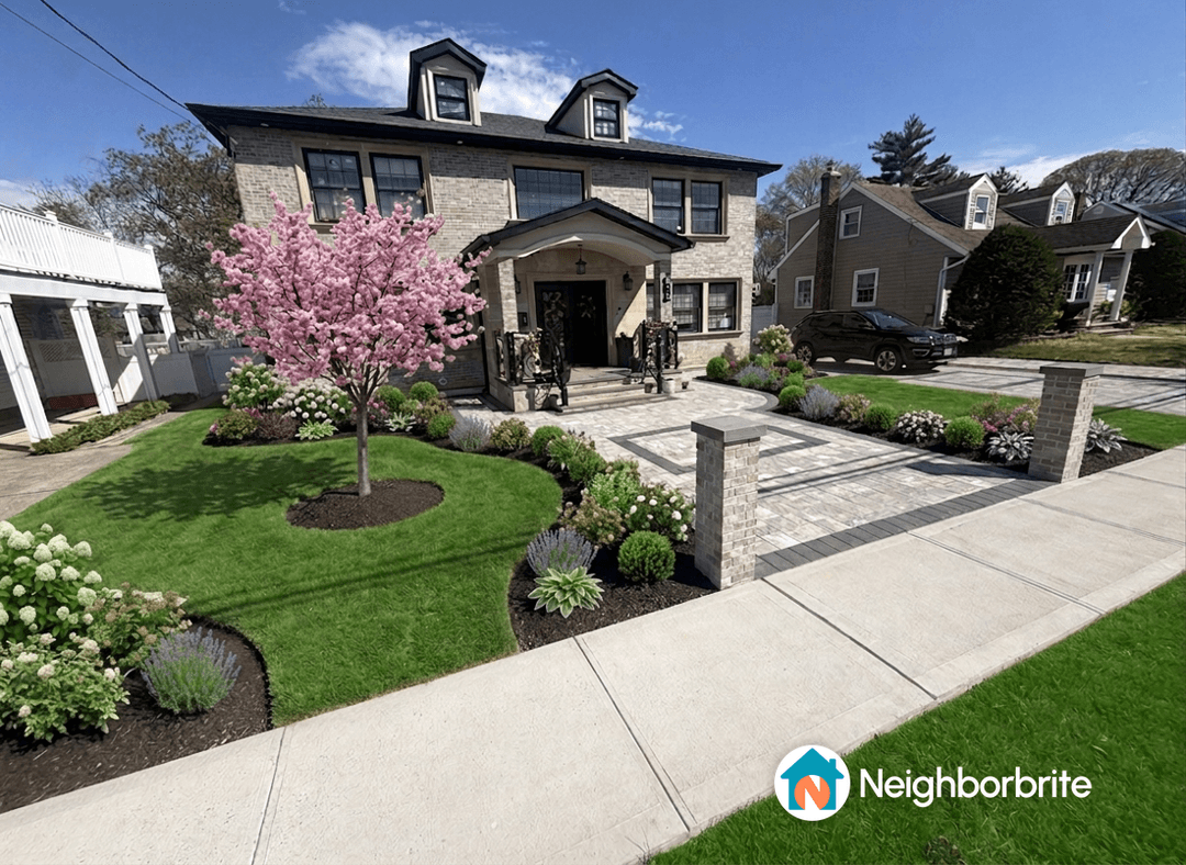 A front yard with a pink flowering tree and various plants.