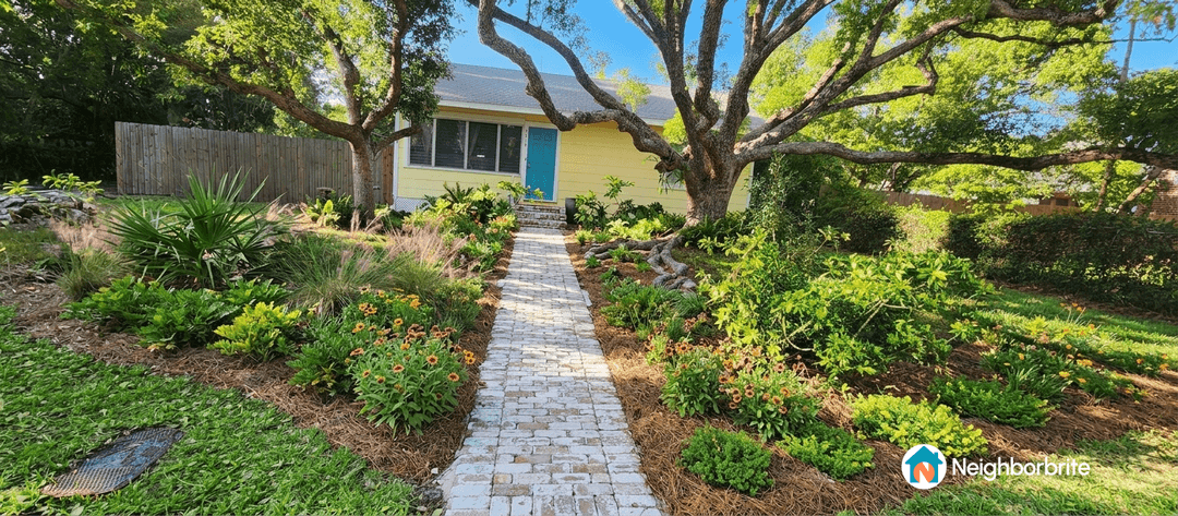 A landscaped yard with a stone path and colorful flowers.