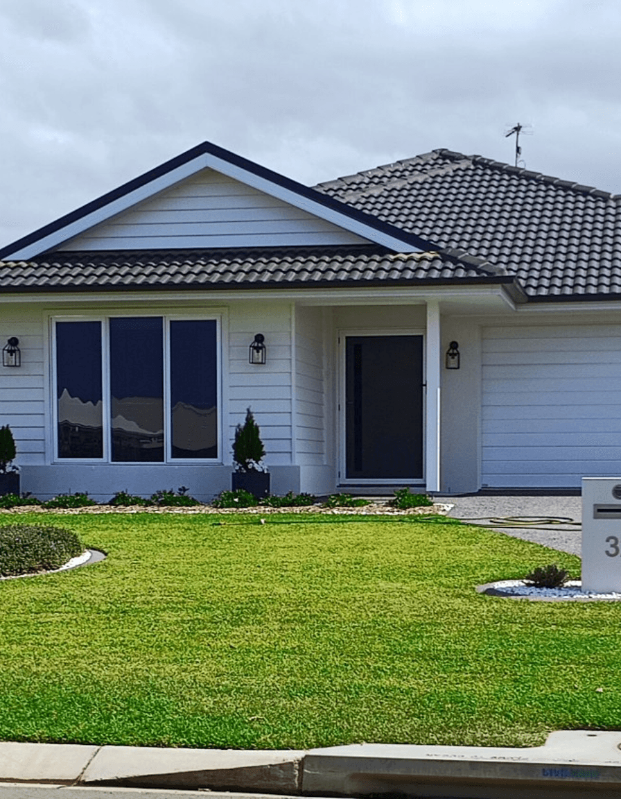 A modern house with a porch and well-maintained lawn.