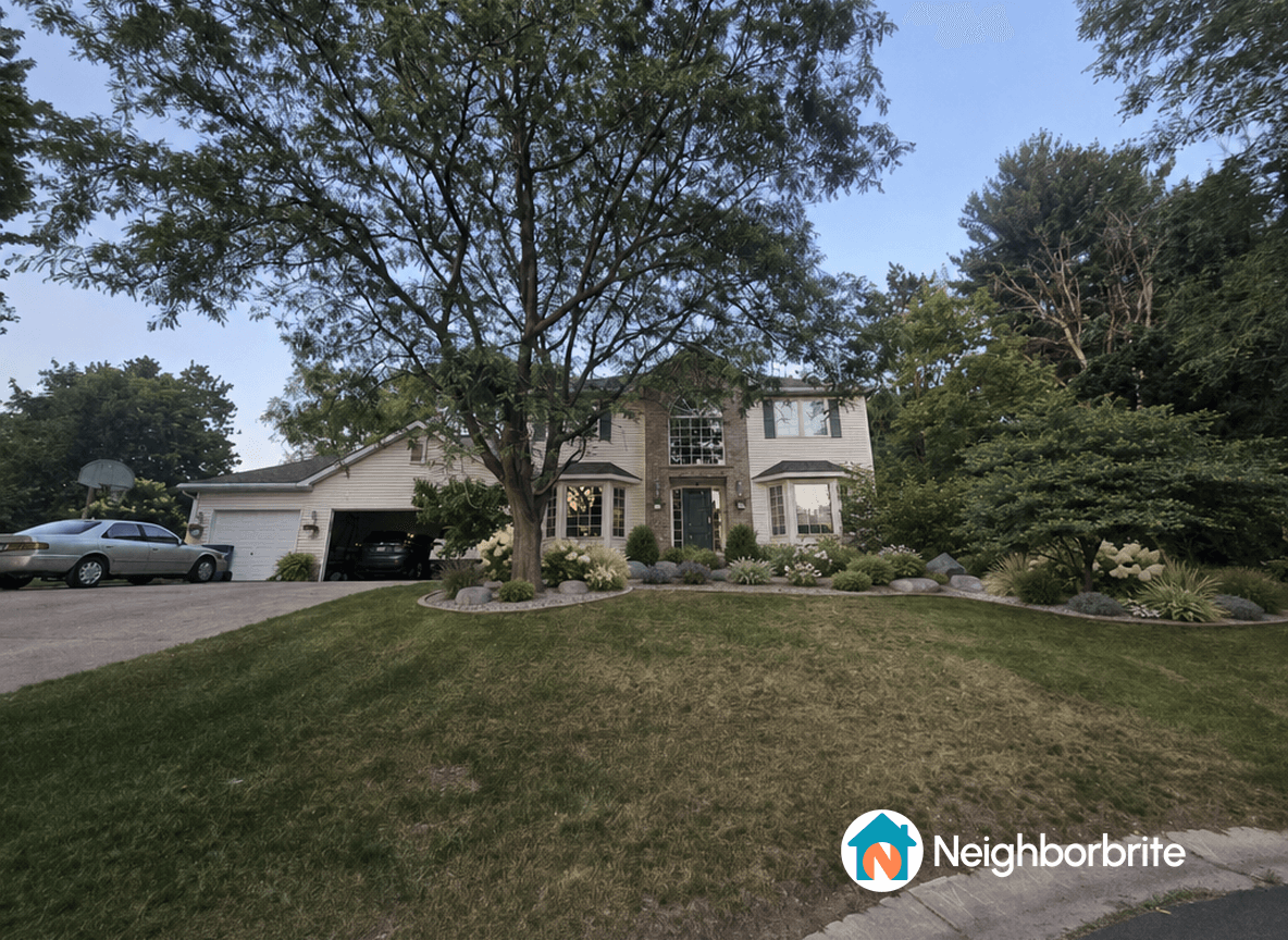 A well-maintained home with lush landscaping and a large tree.