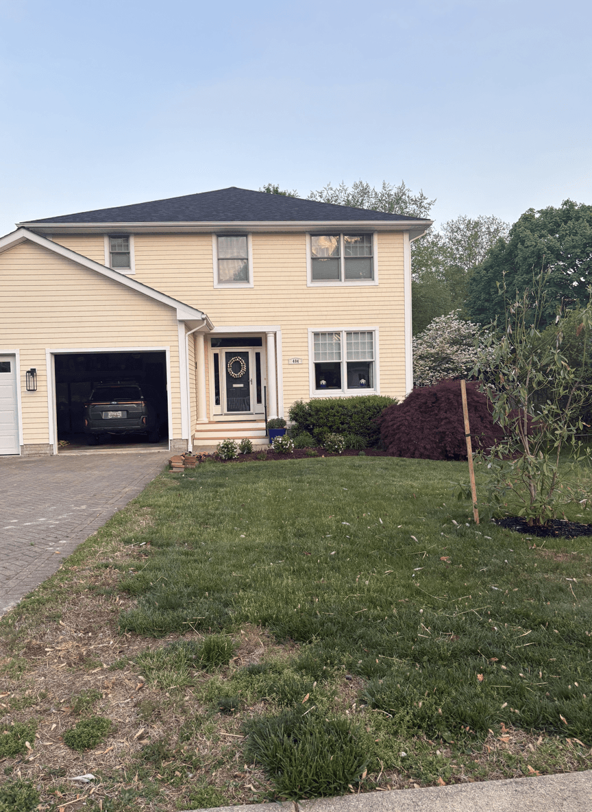 Front yard of a house with grass and some plants, seeking landscaping suggestions.