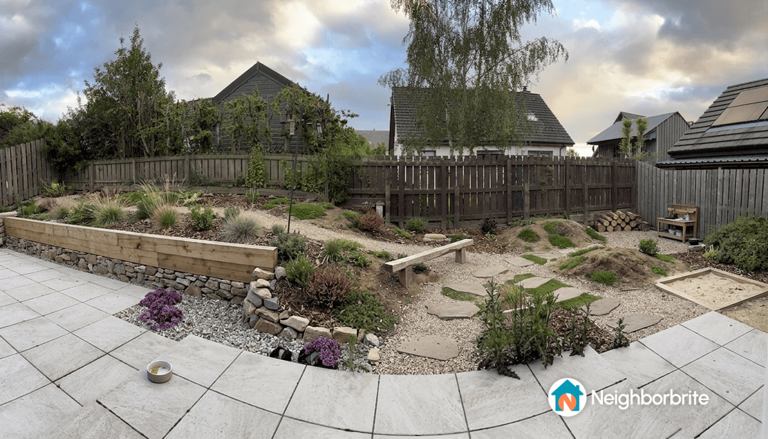 A garden with various plants, a patio, and a wooden bench.