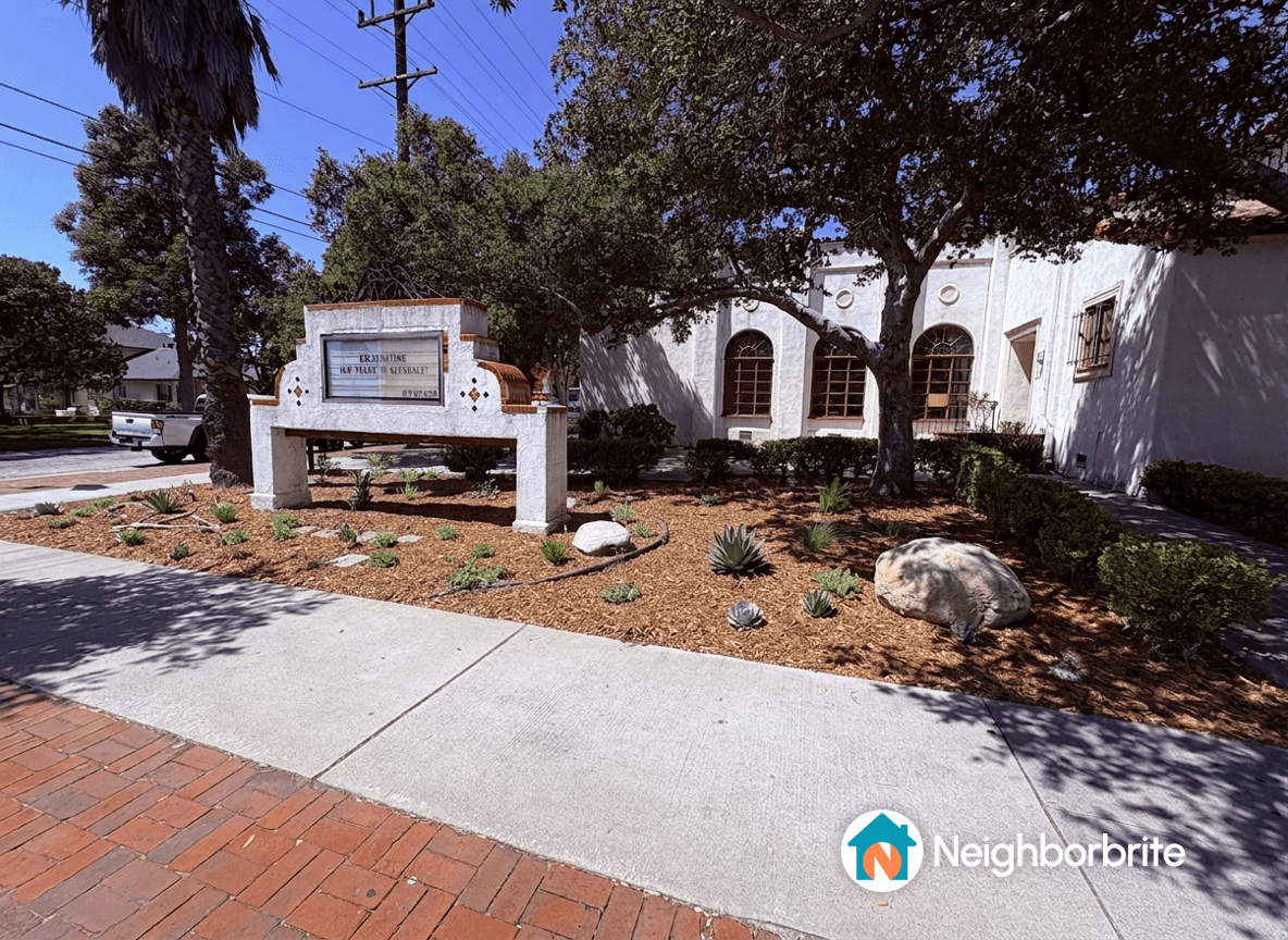 Landscaped area with plants and a sign outside a building.