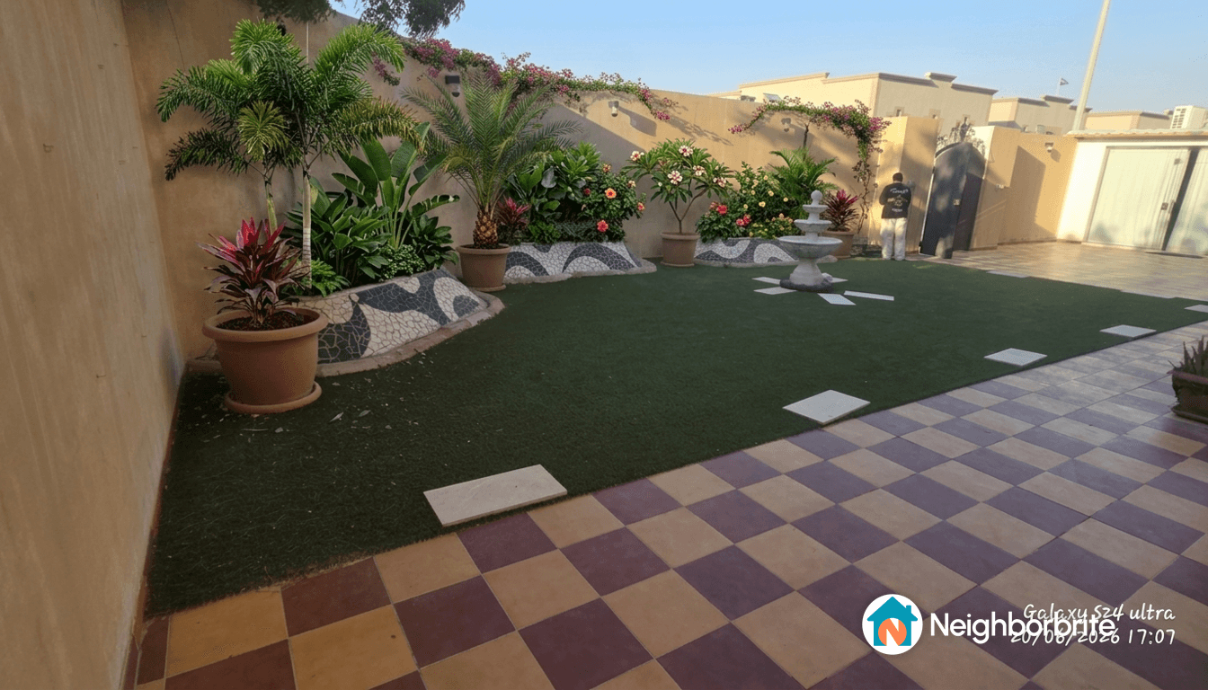A landscaped yard with plants, a fountain, and patterned tiles.