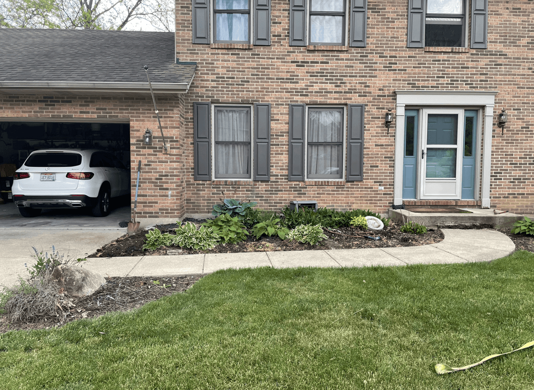 Front bed of a house with existing plants and landscaping.