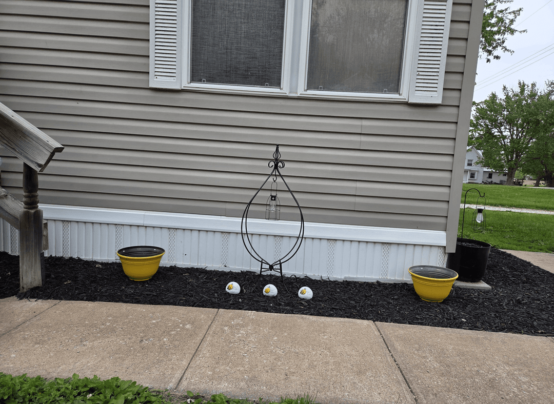 A front yard with decorative pots and bee-themed ornaments.