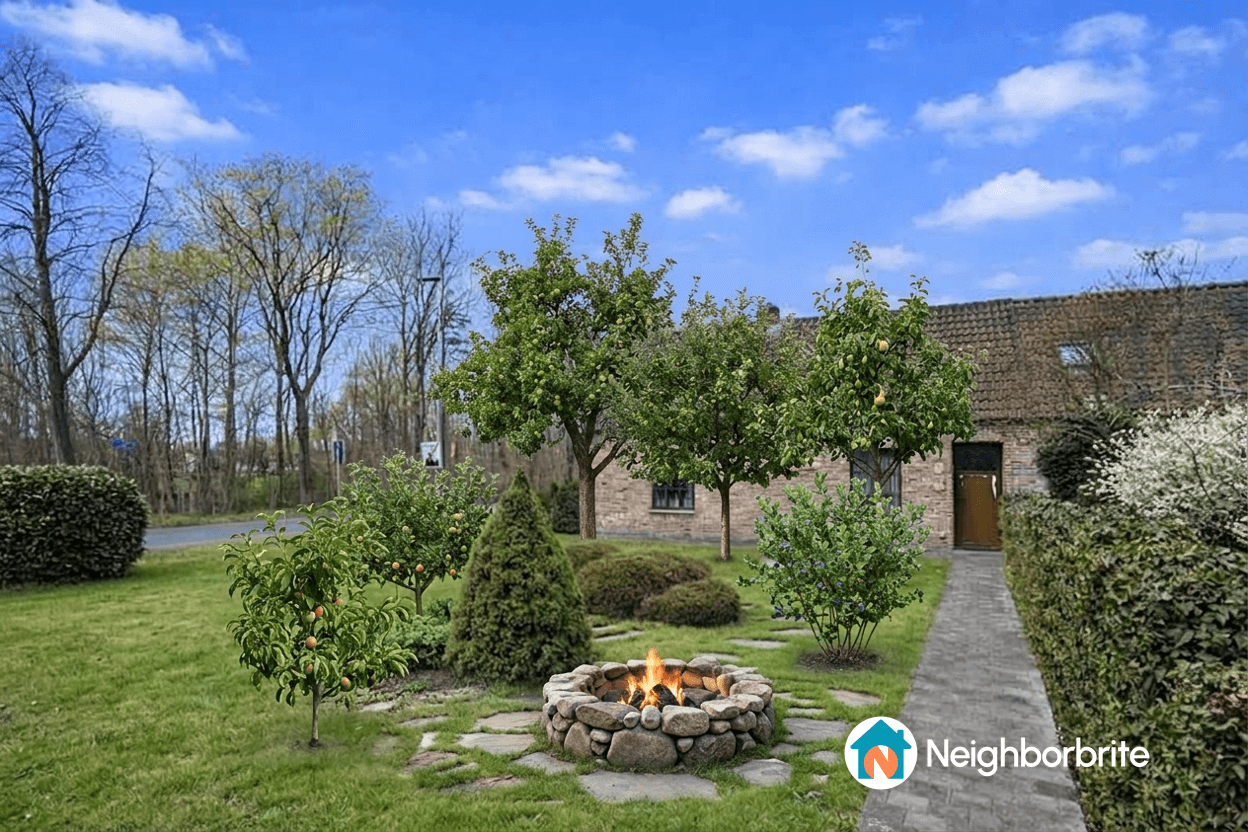 A serene garden featuring a stone fire pit surrounded by trees and greenery.