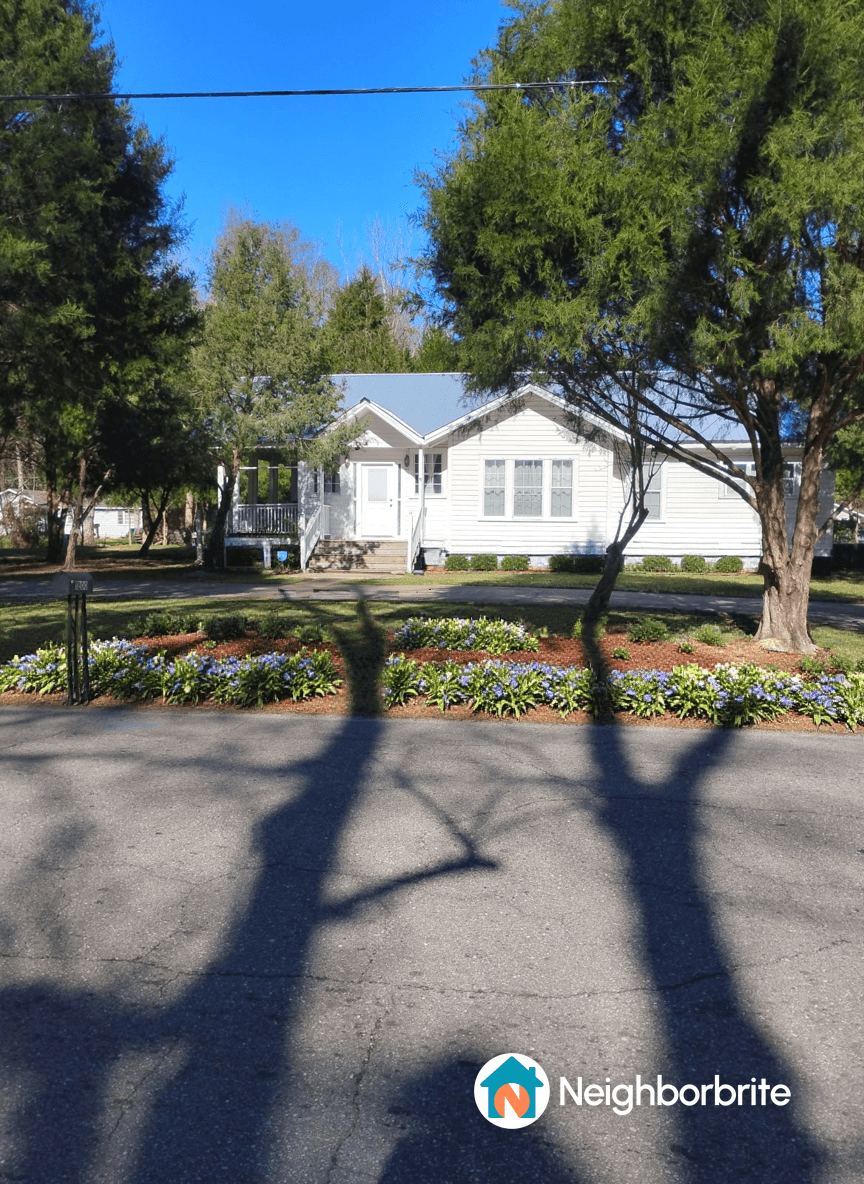 A house with a flower bed in front, seeking drought-tolerant plant suggestions.