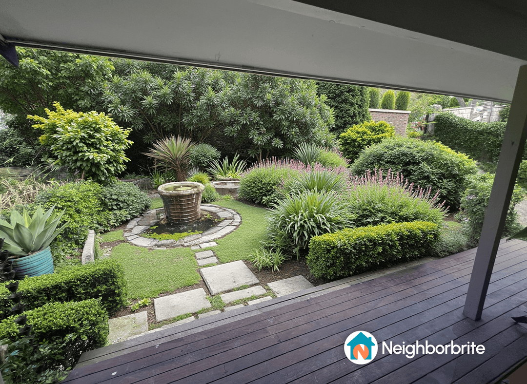 A beautiful garden featuring a fountain, lush greenery, and colorful plants.