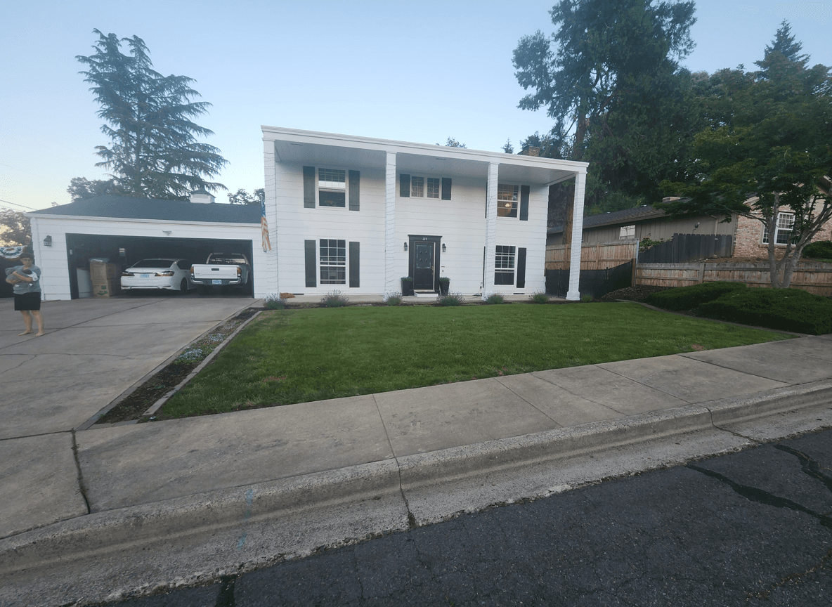 Front yard of a colonial home with green lawn and driveway.