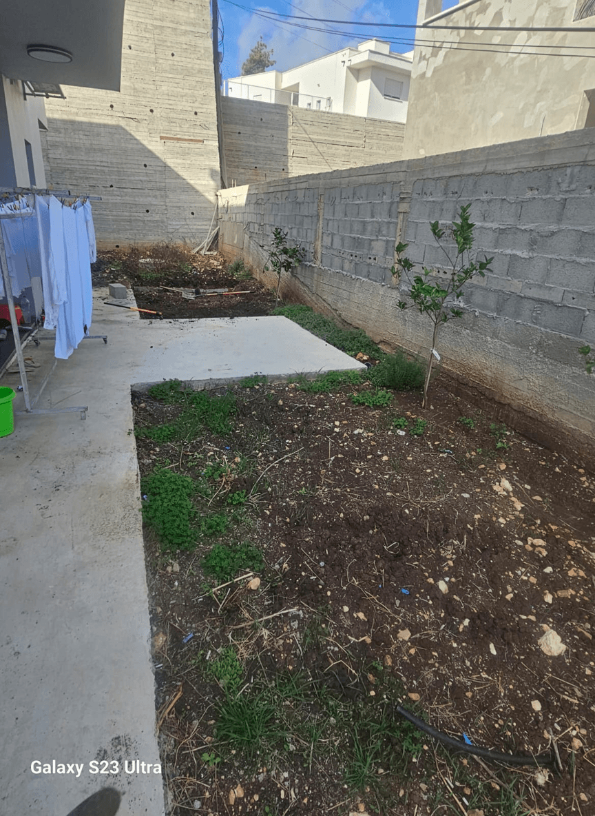 A yard with a wall, featuring wood cladding and stone borders.