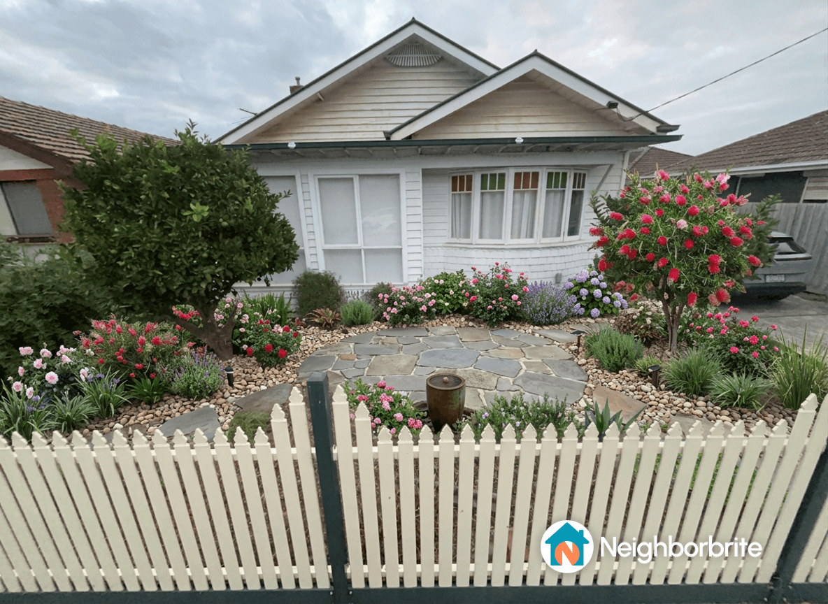 A beautifully landscaped yard with flowers, stones, and a tree.